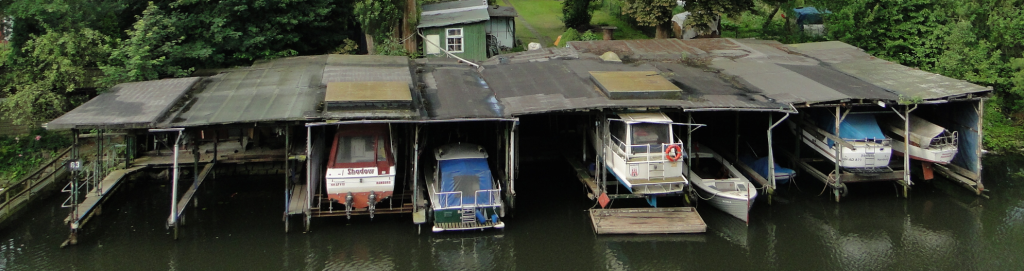 Selbstgefertigte Motor- und Segelboot-Garagen am Anfang des Kanals